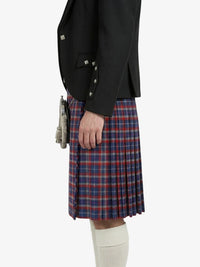 Person wearing a black blazer and red, blue, and white plaid kilt on a white background