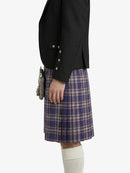 Person wearing a black blazer and plaid kilt on a white background