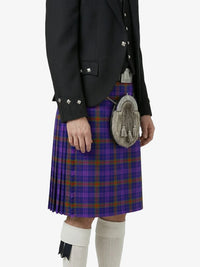 Person wearing a purple plaid kilt with a black jacket and white knee-high socks on a white background