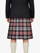 Person wearing a black jacket and plaid kilt on a white background