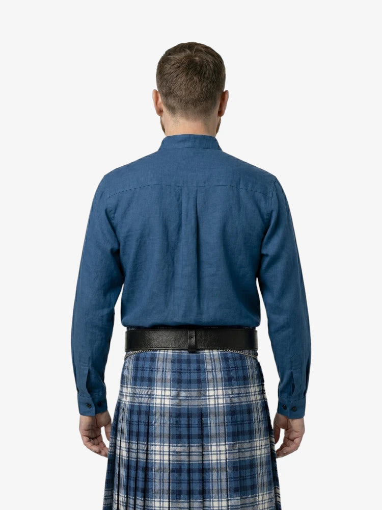 Man wearing a blue shirt and plaid kilt on a white background