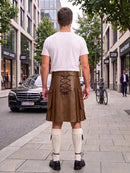 A man viewed from behind wearing a brown leather kilt with lace-up back detailing, a white t-shirt, white knee-high socks, and black shoes, standing on a city sidewalk.