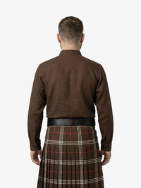 Man wearing a brown shirt and tartan kilt on a white background