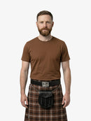 Man wearing a brown t-shirt and plaid kilt on a white background