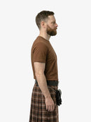 Man wearing a brown t-shirt and plaid kilt on a white background
