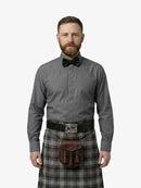 Man wearing a gray shirt, bow tie, and plaid kilt on a white background