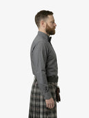 Man wearing a gray shirt and plaid kilt on a white background