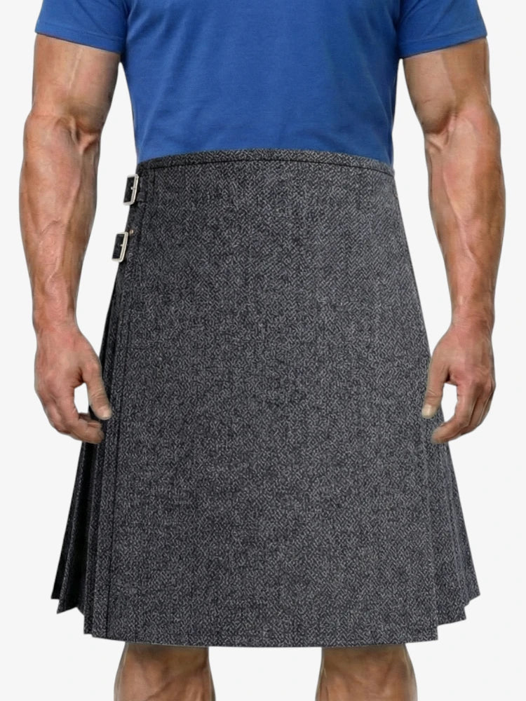Person wearing a gray patterned kilt over a blue shirt on a white background