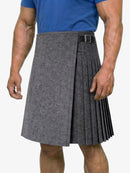 Person wearing a gray pleated kilt with a blue shirt on a white background