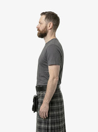 Man wearing a gray t-shirt and plaid kilt on a white background
