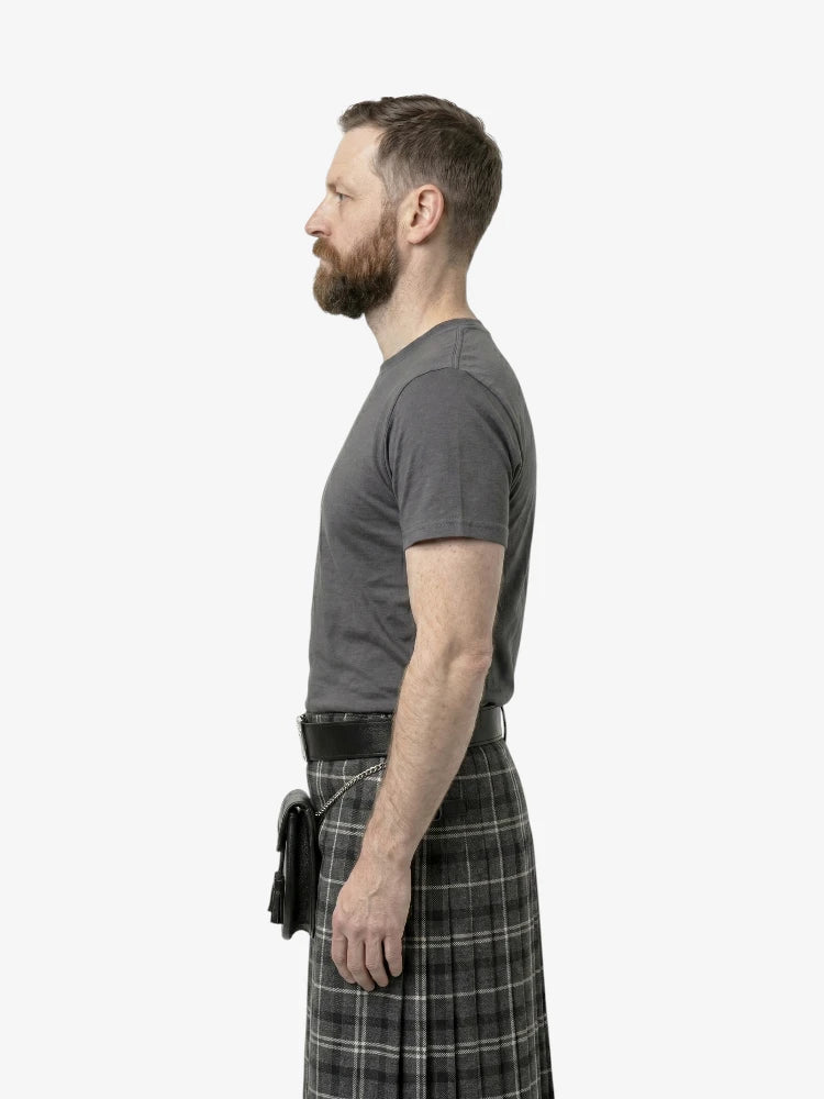Man wearing a gray t-shirt and plaid kilt on a white background