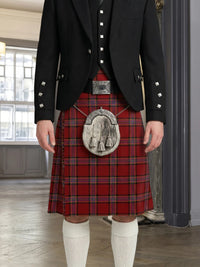 Person wearing a traditional Scottish kilt with a jacket indoors.