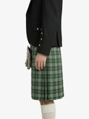 Person wearing a black jacket and green plaid kilt on a white background