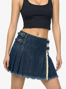 Person wearing a black crop top and denim skirt with buckles on a white background