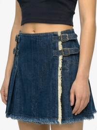 Denim skirt with metal buckles worn by a person on a white background