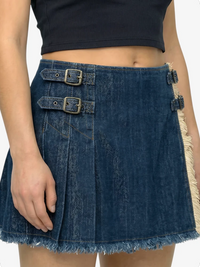 Person wearing a blue denim skirt with metal buckles on a white background