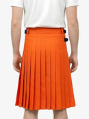 Person wearing an orange pleated skirt with a white top on a white background