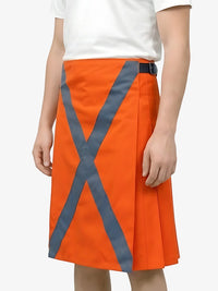 Orange skirt with reflective gray stripes worn by a person on a white background