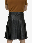 Person wearing a brown top and black pleated leather skirt on a white background