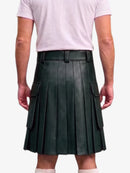 A dark forest green pleated faux leather kilt with side cargo pockets, modeled from the back on a person wearing a light pink t-shirt against a white background.