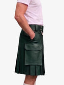 A dark green faux-leather kilt with pleated detailing, a front flap pocket, and a belt with silver-tone buttons, shown on a model wearing a light pink t-shirt against a white background.