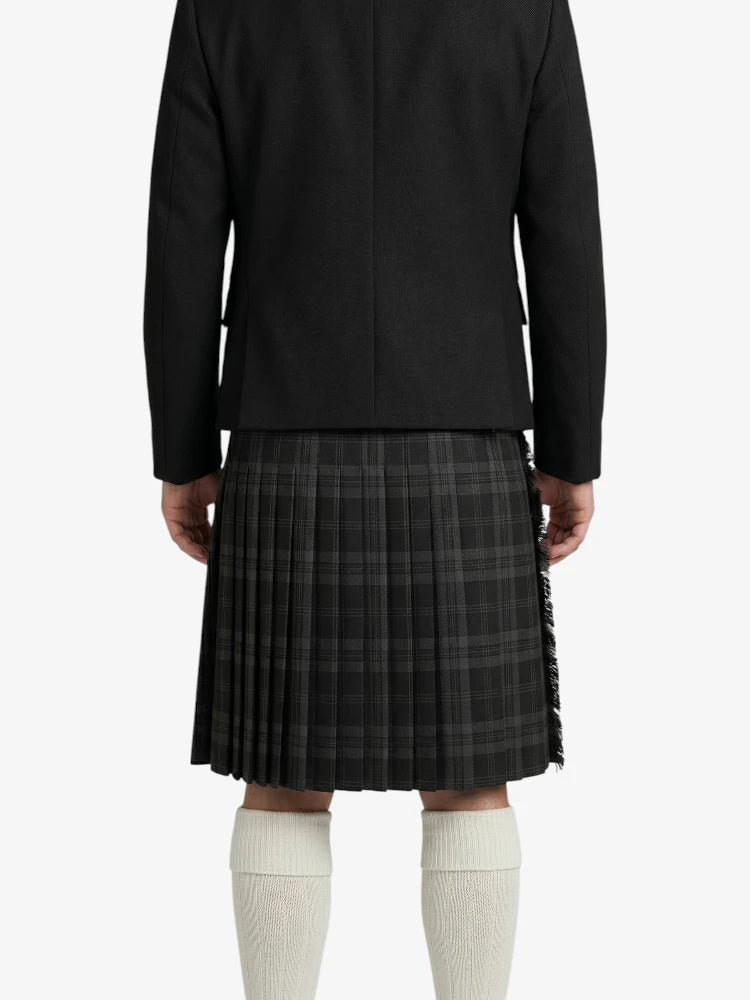 Person wearing a black jacket and plaid kilt on a white background