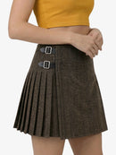 Brown pleated skirt with black buckles worn by a person on a white background