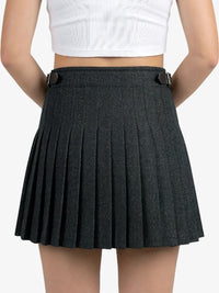 Person wearing a black pleated skirt on a plain background