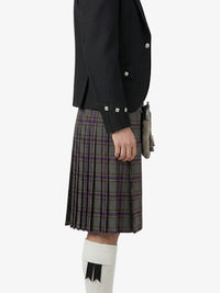 Person wearing a black jacket and plaid kilt on a white background