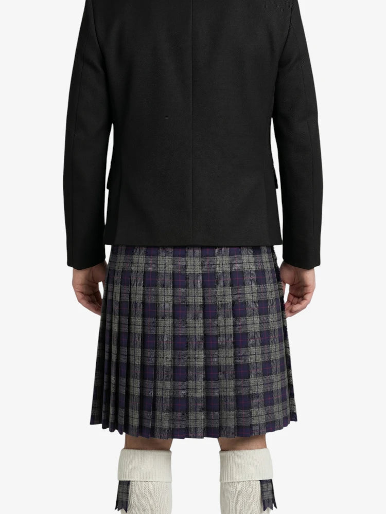 Person wearing a black jacket and plaid kilt on a white background