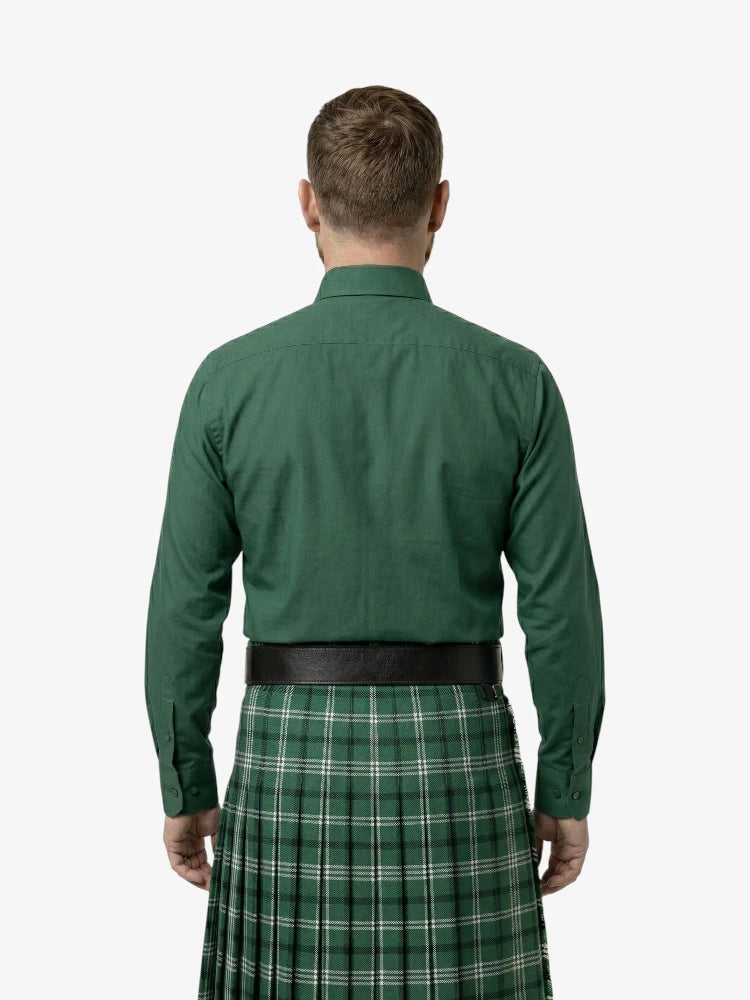 Man wearing a green shirt and green plaid kilt on a white background