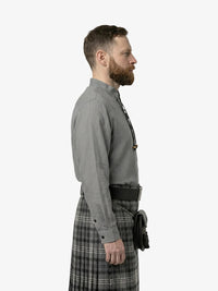 Man wearing a gray shirt and plaid kilt on a white background
