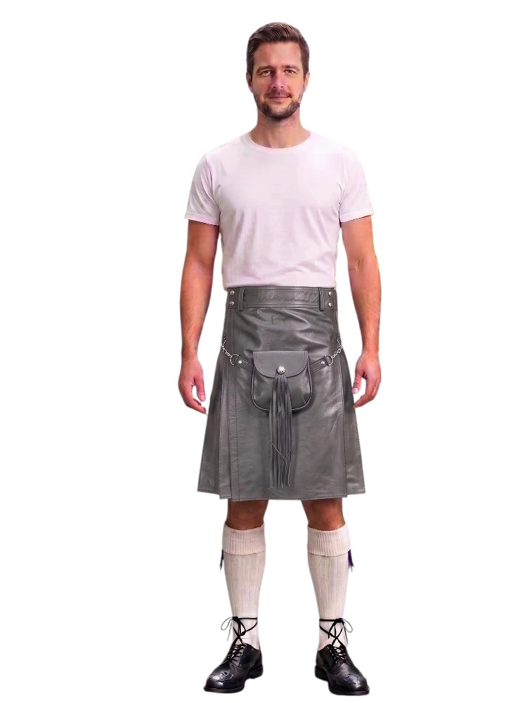 A man modeling a gray faux-leather kilt with a matching belt and pouch, paired with a white t-shirt, cream knee-high socks, and black lace-up shoes, against a plain white background.