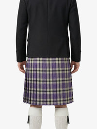 Person wearing a black coat and plaid kilt on a white background
