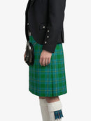Person wearing a green plaid kilt with a black jacket on a white background