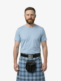Man wearing a light blue t-shirt and plaid kilt on a white background