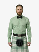 Man wearing a green shirt, bow tie, and tartan kilt on a white background