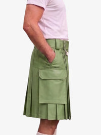 A person wearing a light sage green faux-leather kilt with pleated detailing, a belt, and a large front cargo pocket, paired with a light pink t-shirt against a plain white background.
