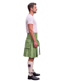 A man shown in profile wearing a light green kilt, a white t-shirt, white knee-high socks, and black leather shoes, photographed against a solid white background.