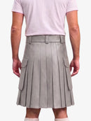 A person shown from the back wearing a light gray pleated mini skirt with side flap pockets and a matching belt, paired with a pale pink T-shirt against a light gray studio background.