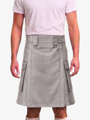 A man wearing a light gray faux-leather kilt with silver-tone hardware, side cargo pockets, and a matching gray belt, paired with a light pink t-shirt.