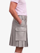 A person wearing a light gray pleated kilt-style skirt with a belt and large front flap pocket, paired with a pale pink short-sleeve top, against a plain light background.