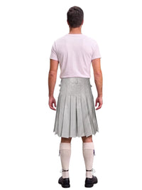 A man shown from the back wearing a light gray pleated kilt, a pale pink t-shirt, cream-colored knee-high socks, and black shoes, set against a plain white background.