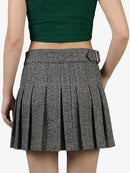 Person wearing a green crop top and pleated skirt on a white background