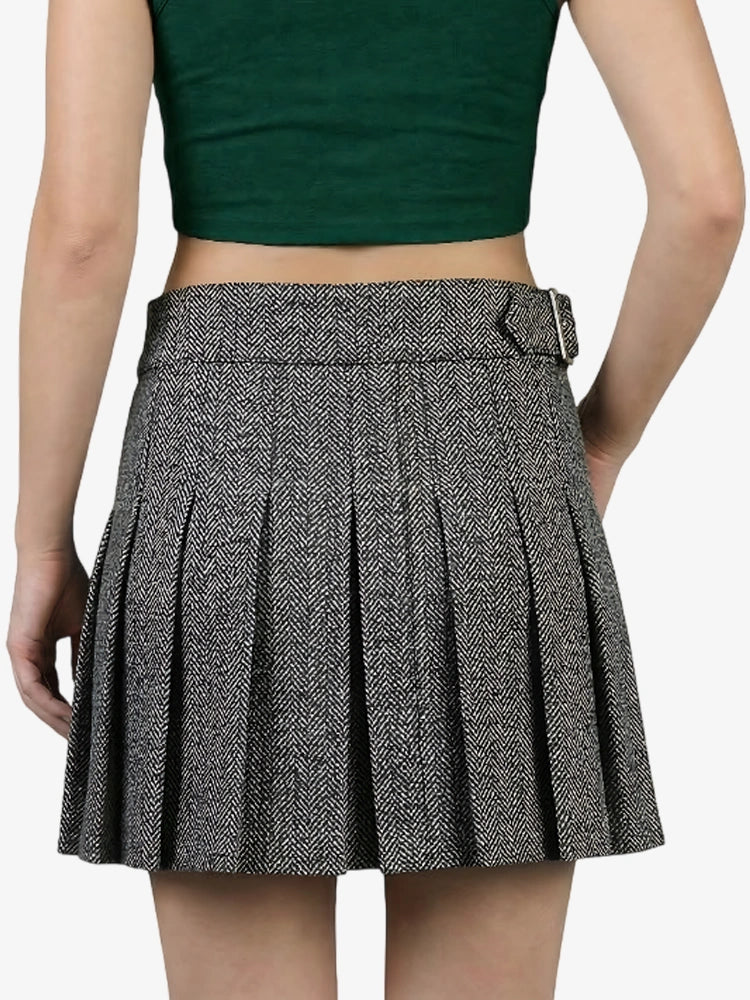 Person wearing a green crop top and pleated skirt on a white background