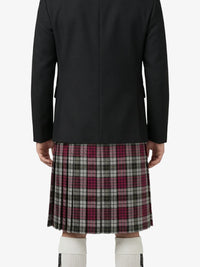 Person wearing a black coat and plaid kilt on a white background