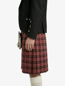 Person wearing a black jacket and red plaid kilt on a white background