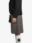 Person wearing a black blazer and plaid kilt on a white background