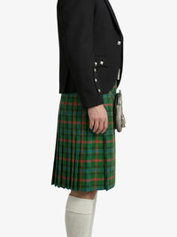 Person wearing a black blazer and green plaid kilt on a white background