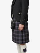 Person wearing a black jacket and plaid kilt on a white background